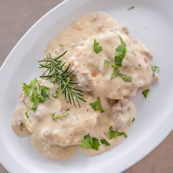 Biscuits and gravy from Uptown Joes New York Diner, garnished with fresh rosemary and parsley.