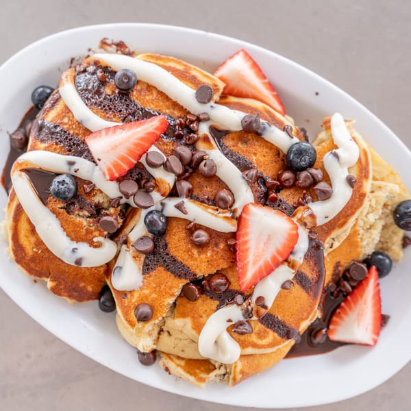Uptown Joes New York Diner's chocolate chip pancakes with strawberries, blueberries, and cream drizzle.