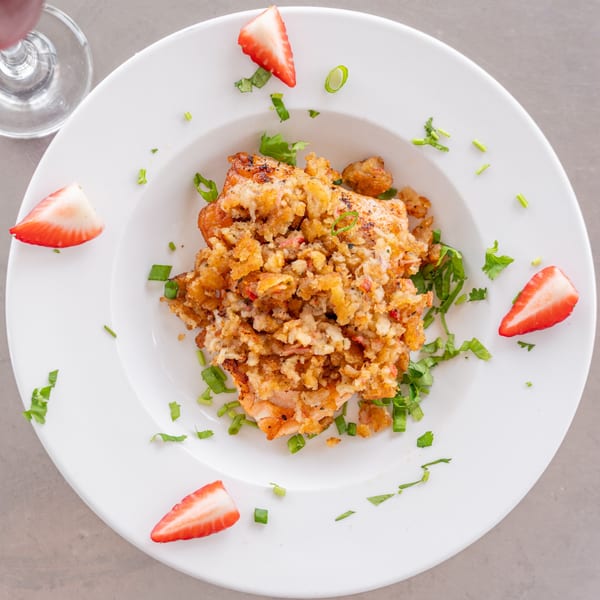 Uptown Joes' breakfast dish with crispy topping, garnished with fresh strawberries and herbs.